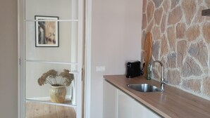 Una cocina moderna con pared de piedra, encimera de madera y lavabo empotrado.