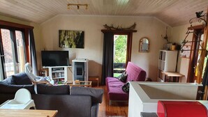 A cozy living room with a fireplace, a television, a sofa, a pink couch, and a dining area with a table and chairs.