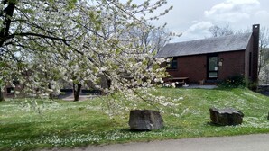 A brick building with a sloped roof, a bench, and a stone pathway leading to it.
