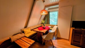 A cozy room with a wooden dining table, a sofa, and a TV.