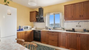 A kitchen with wooden cabinets, a microwave, a stove, and a window.