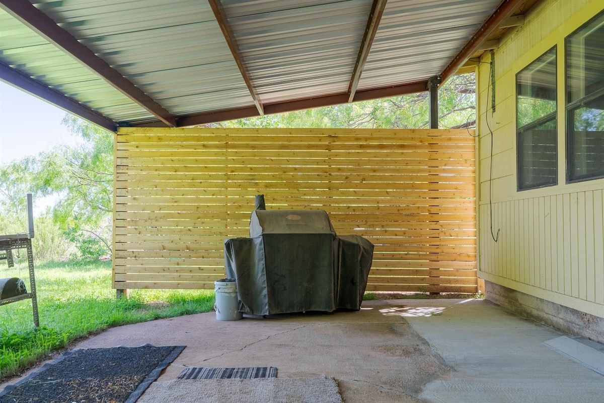 A covered outdoor area with a grill and a metal rack.