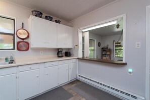 Cocina con armarios blancos, cafetera y ventana.