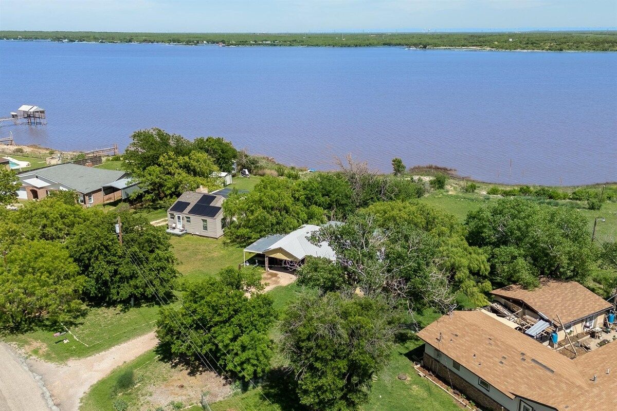 A residential area with houses surrounded by trees and a large body of water.