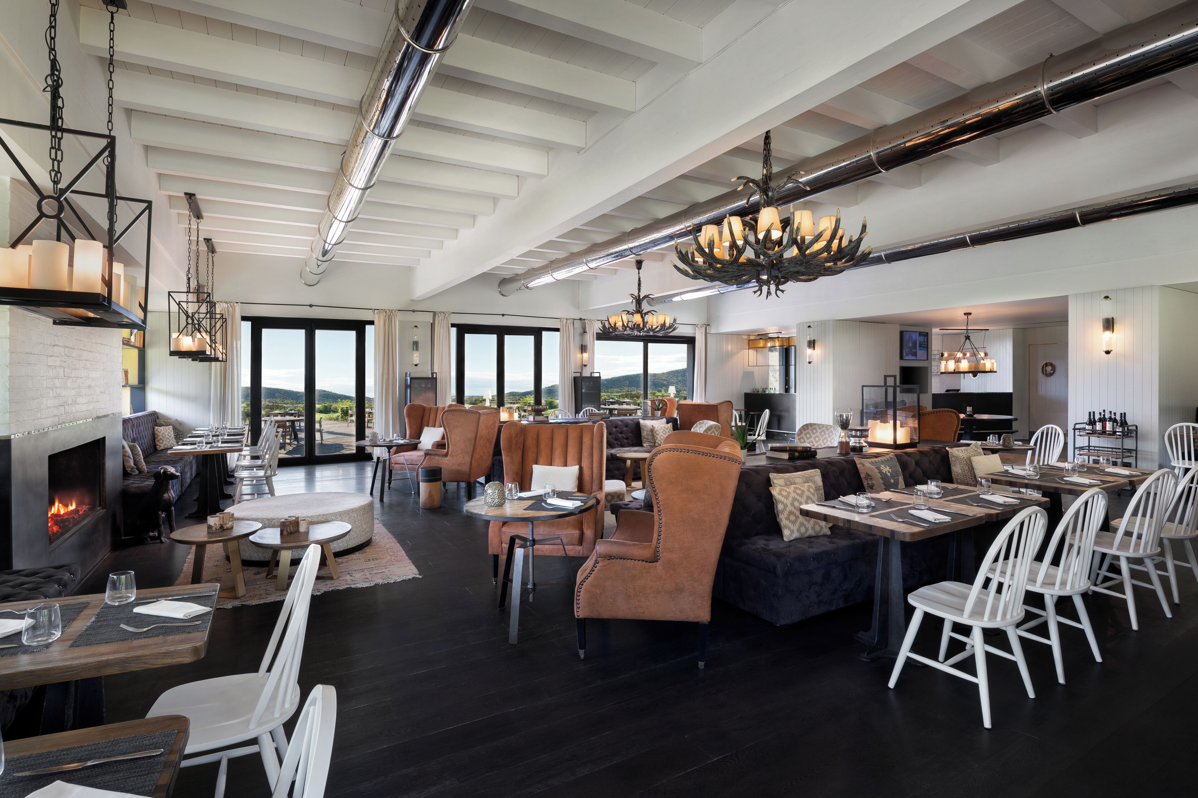 A spacious indoor area with a fireplace, seating arrangements, and a view through large windows.