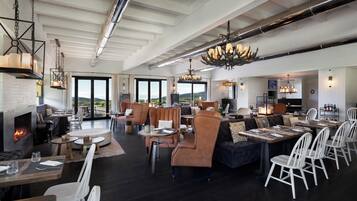 A spacious indoor area with a fireplace, seating arrangements, and a view through large windows.