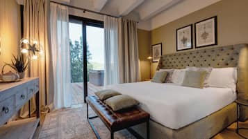 A spacious bedroom with a large bed, a bench, a bedside table, and a view through a glass door.