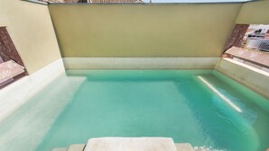 A rectangular swimming pool with clear water, surrounded by a low wall and a small set of steps leading into the water. - Charm & history in the heart of VRSA (Vila Real de Santo António)