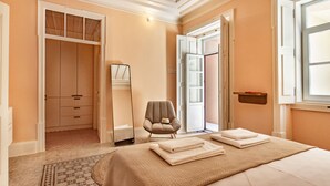 A hotel room with a bed, a chair, a wardrobe, and a mirror. - Charm & history in the heart of VRSA (Vila Real de Santo António)
