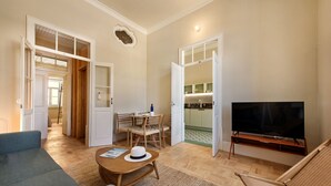 A living room with a sofa, a coffee table, a TV, and a dining area with chairs and a table.