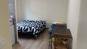 A small, compact room with a bed, a desk, and a chair. The room has a wooden floor and white walls. - Studio for 3 people - Bilbao (Bilbao)