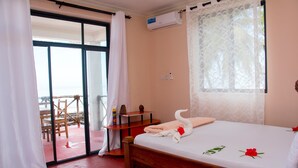 Une chambre d’hôtel avec un lit, une petite table, une chaise et une vue à travers une porte vitrée.