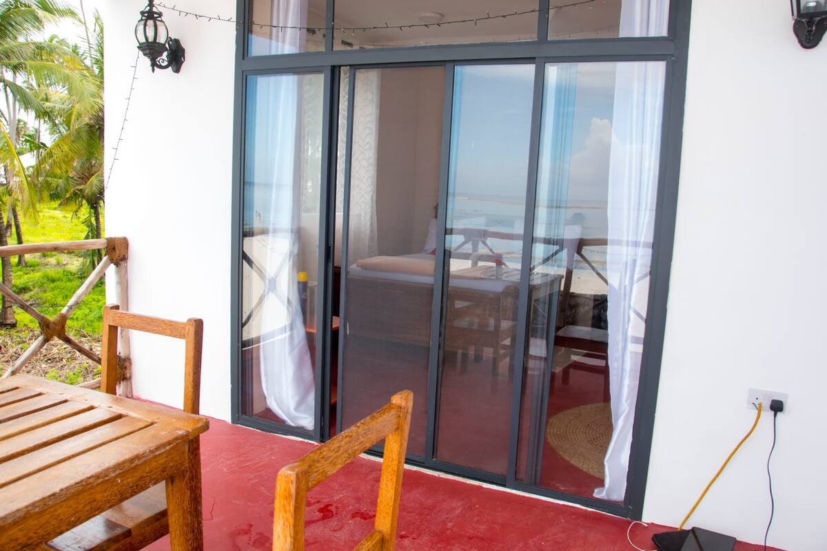 A room with a sliding glass door leading to a balcony with a wooden table and chairs.