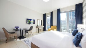 Une chambre d’hôtel avec un lit, un bureau, deux chaises, une télévision et une vue sur la ville.