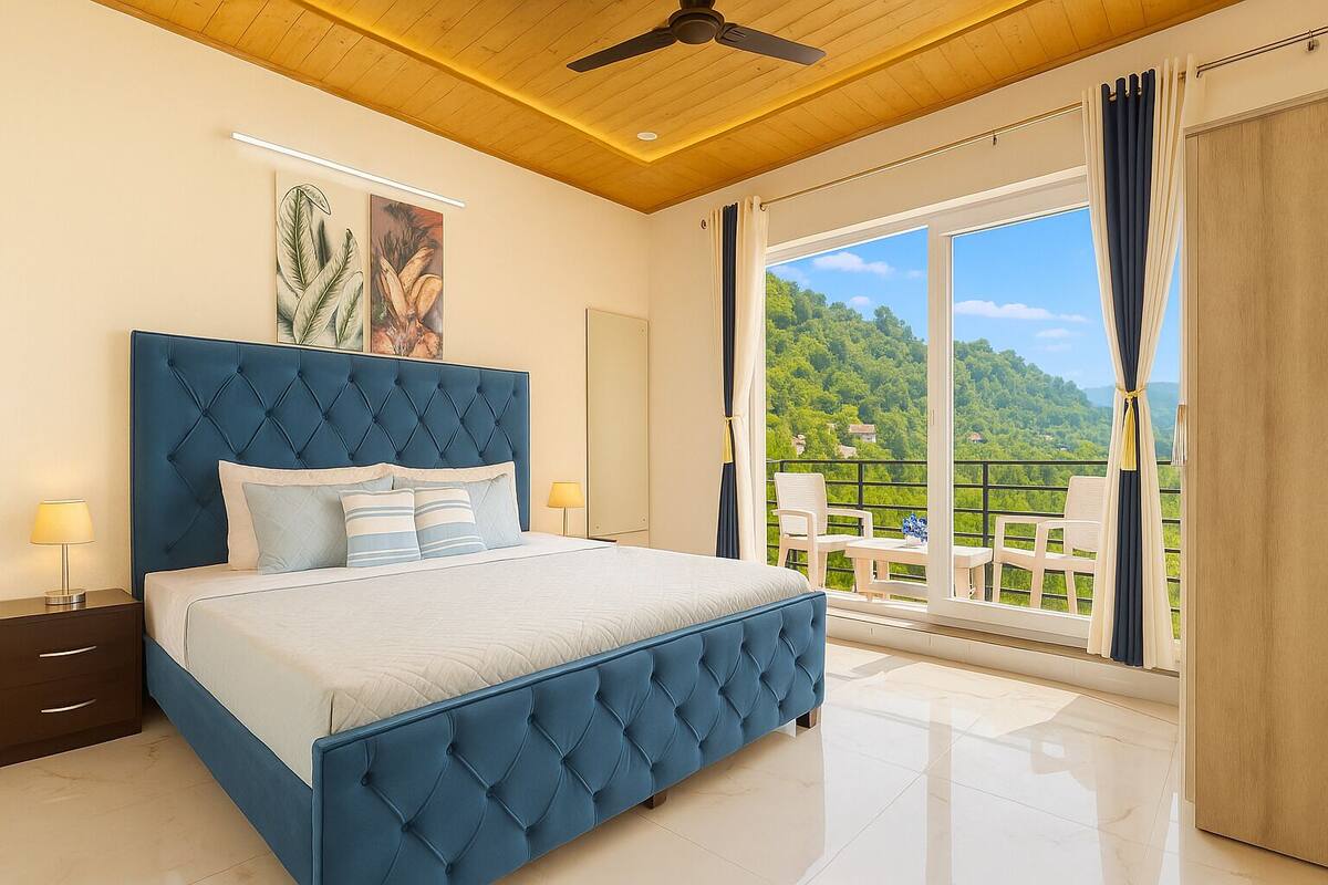 A bedroom with a large bed, a ceiling fan, and a balcony with a view of greenery.