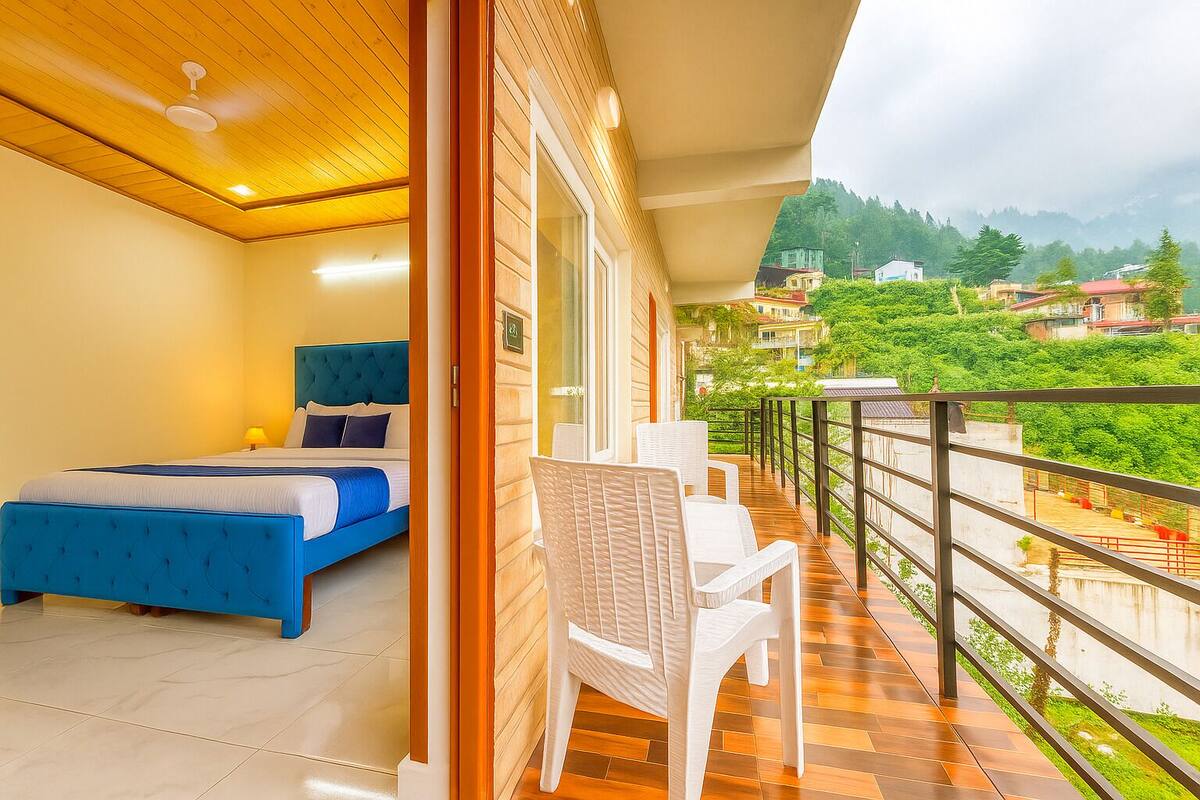 A bedroom with a bed, a chair, and a balcony with a view of the surrounding area.