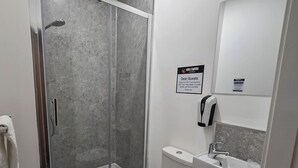 A modern bathroom with a glass-enclosed shower, a white toilet, and a sink with a mirror above it. - Hullywood Rooms (Hull)