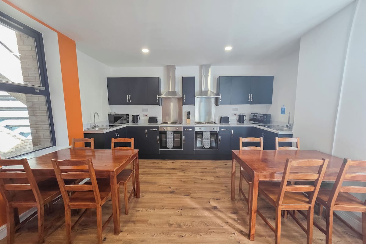 A modern kitchen with black cabinets, stainless steel appliances, and a wooden dining table with chairs.