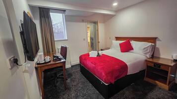 Une chambre d’hôtel équipée d’un lit, d’un bureau, d’une chaise, d’une machine à café et d’une table de chevet.