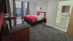 Una habitación de hotel con una cama, mesita de noche y un escritorio pequeño.