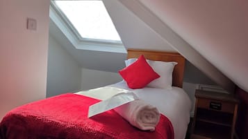 Ein ordentlich bezogenes Bett mit roter und weißer Bettwäsche, ein Oberlicht darüber und ein Nachttisch mit einem Schild, auf dem 'Hollywood Hotel' steht.