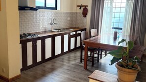 Une cuisine de taille réduite comprenant un coin repas, des meubles en bois, une fenêtre et une plante en pot.