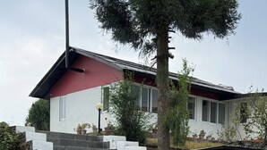 Une maison avec un toit rouge, des murs blancs et un escalier en pierre menant à l’entrée.