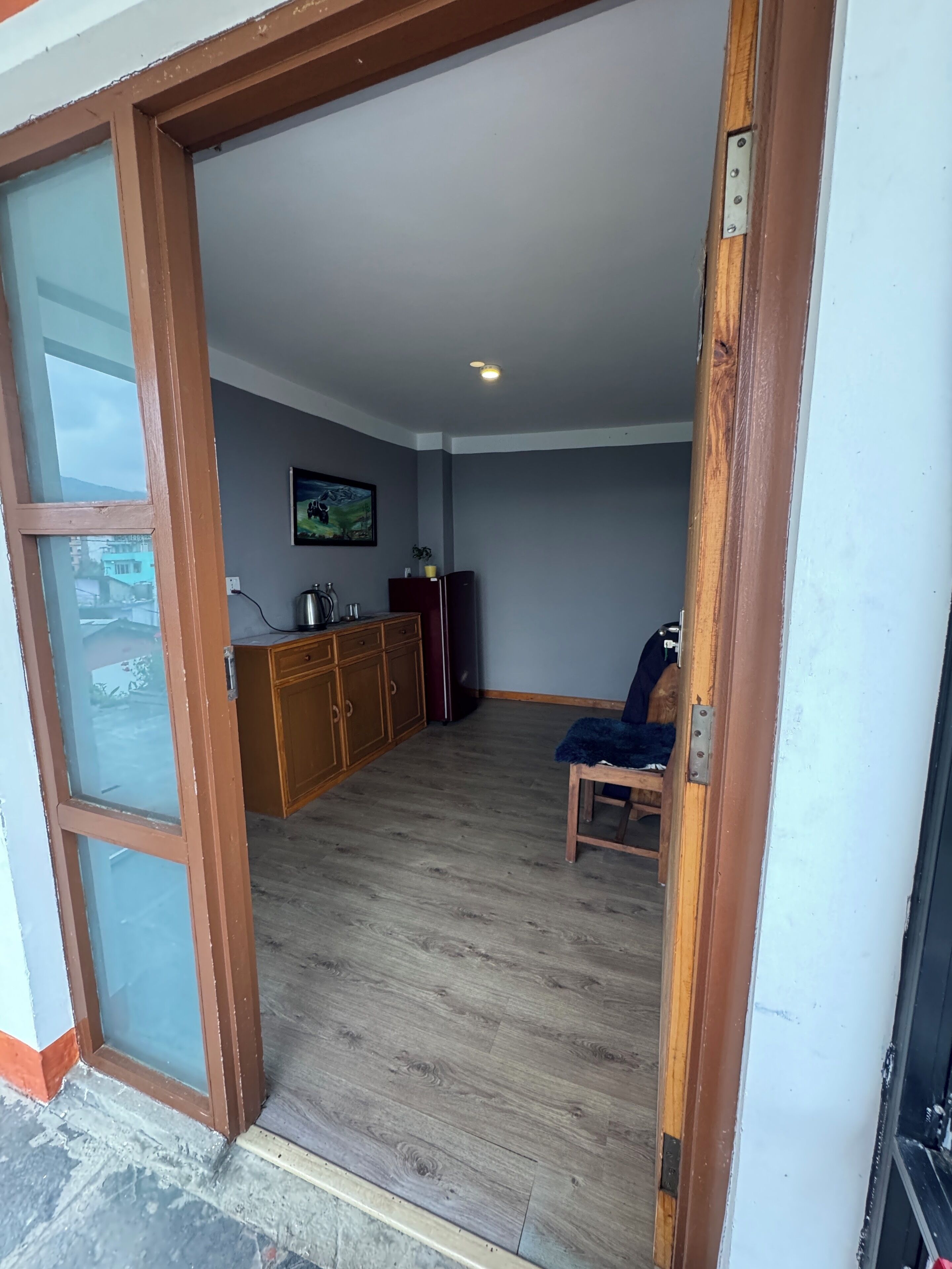 Une pièce avec un plancher en bois, une armoire, une chaise et un tableau accroché au mur.