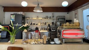 A kitchen with a refrigerator, stove, and various kitchen appliances. There are shelves with dishes and a window with a view. - Haya Hotel Da Nang (Da Nang)