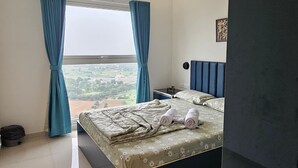 A bedroom with a bed, a ceiling fan, a window with curtains, and a view of the landscape.