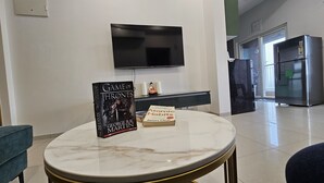 A modern living room with a marble table, a Game of Thrones book, and a book titled 'Atomic Habits' by James Clear.