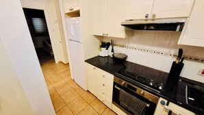 Een kleine keuken met witte kasten, een zwart aanrecht en een fornuis.