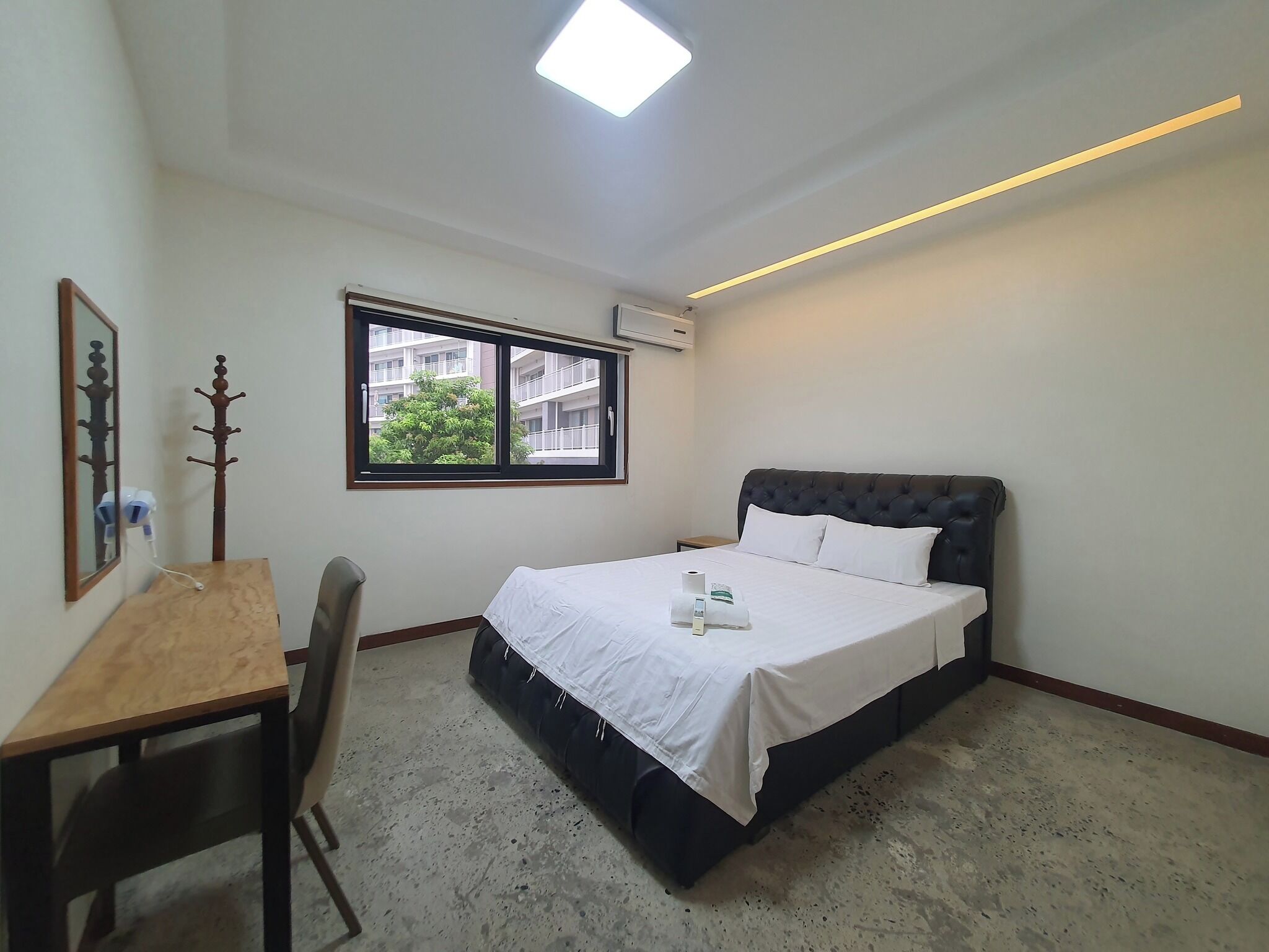 Une chambre à coucher comprenant un lit, un bureau, une chaise, une fenêtre et un luminaire au plafond.