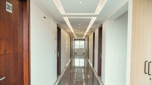 Un corridoio d'hotel con un segnale numerico, porte in legno e pavimento piastrellato.