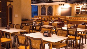 A restaurant interior with multiple tables and chairs, a ceiling with exposed beams, and a wall with a mural. - Snap Inn Rooms By The Buzz House (Anekal)