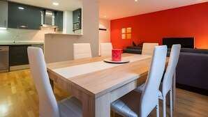Una cocina moderna con armarios oscuros, una mesa de comedor con sillas blancas y una pared de acento roja.