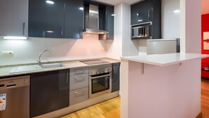 Una cocina moderna con armarios oscuros, un horno de acero inoxidable, un lavavajillas y un microondas.