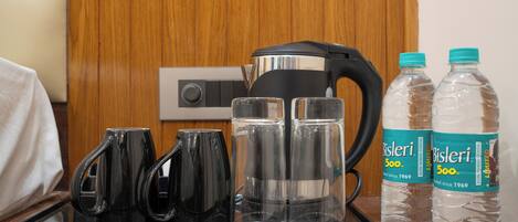 Un plateau avec une bouilloire, quatre tasses et deux bouteilles d’eau Bisleri.