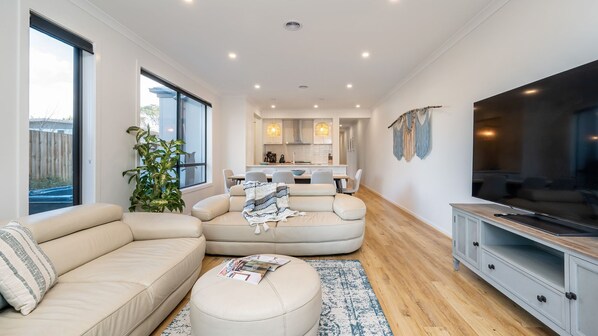 A modern living room with a sofa, ottoman, and a TV stand.