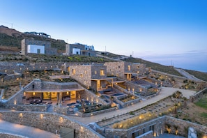 A hillside property with stone buildings, outdoor seating, and a swimming pool. - Panormos Bay Collection (Mykonos)