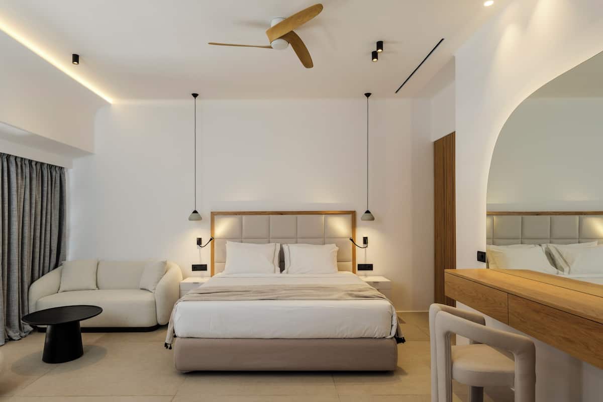 A modern hotel room with a bed, a sofa, a desk, and a chair.
