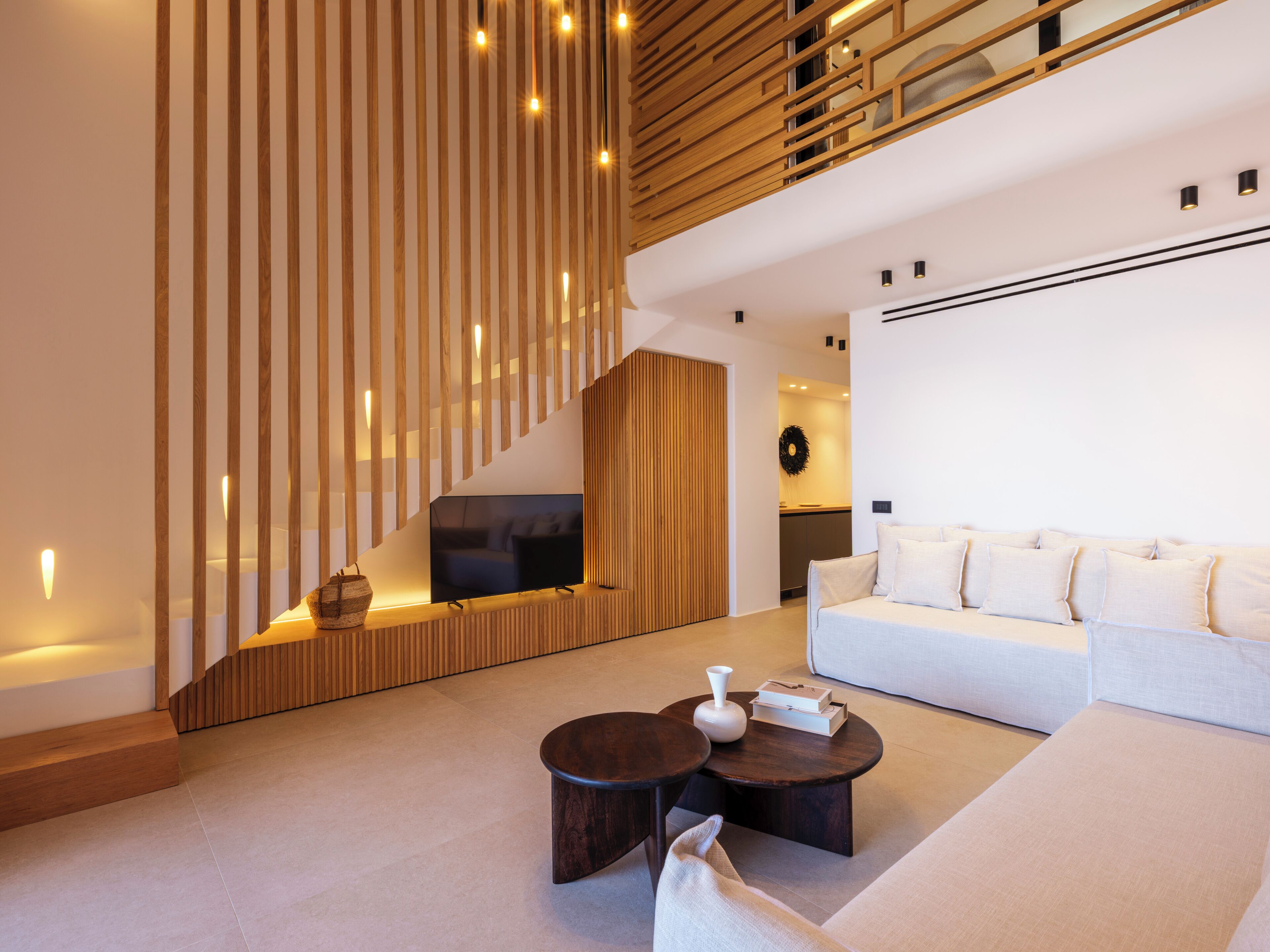 A modern living room with a sofa, coffee table, TV, and wooden slatted wall.