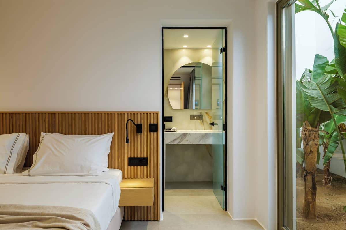 A modern bedroom with a wooden headboard, a bedside table, and a large mirror.