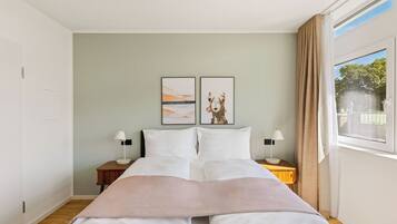 A neatly arranged bedroom with a bed, two bedside tables, and a window with curtains.