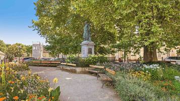 A park with benches, a statue, and flower beds.