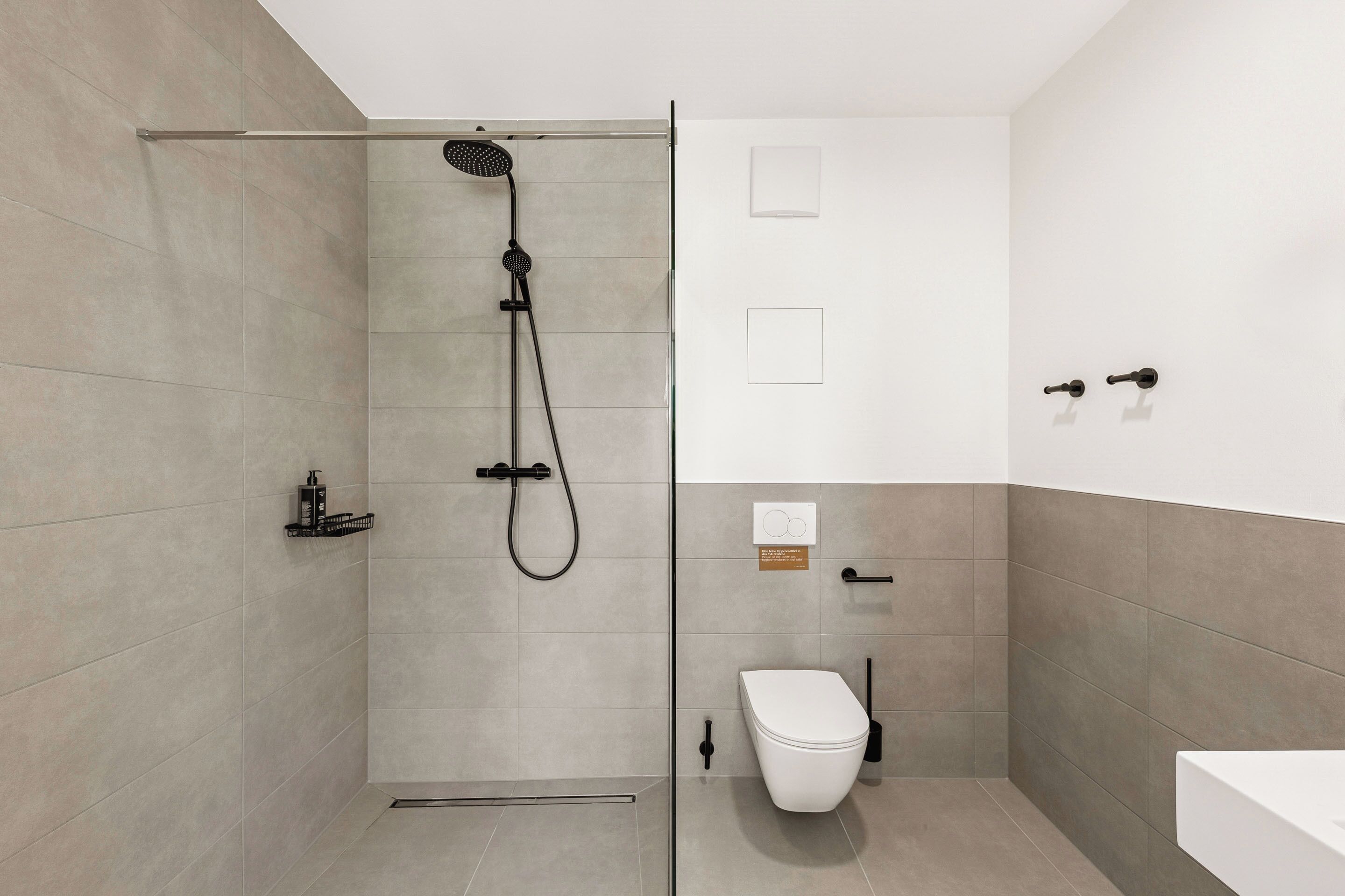 A modern bathroom with a shower, toilet, and sink.