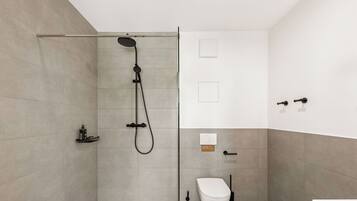 A modern bathroom with a shower, toilet, and sink.