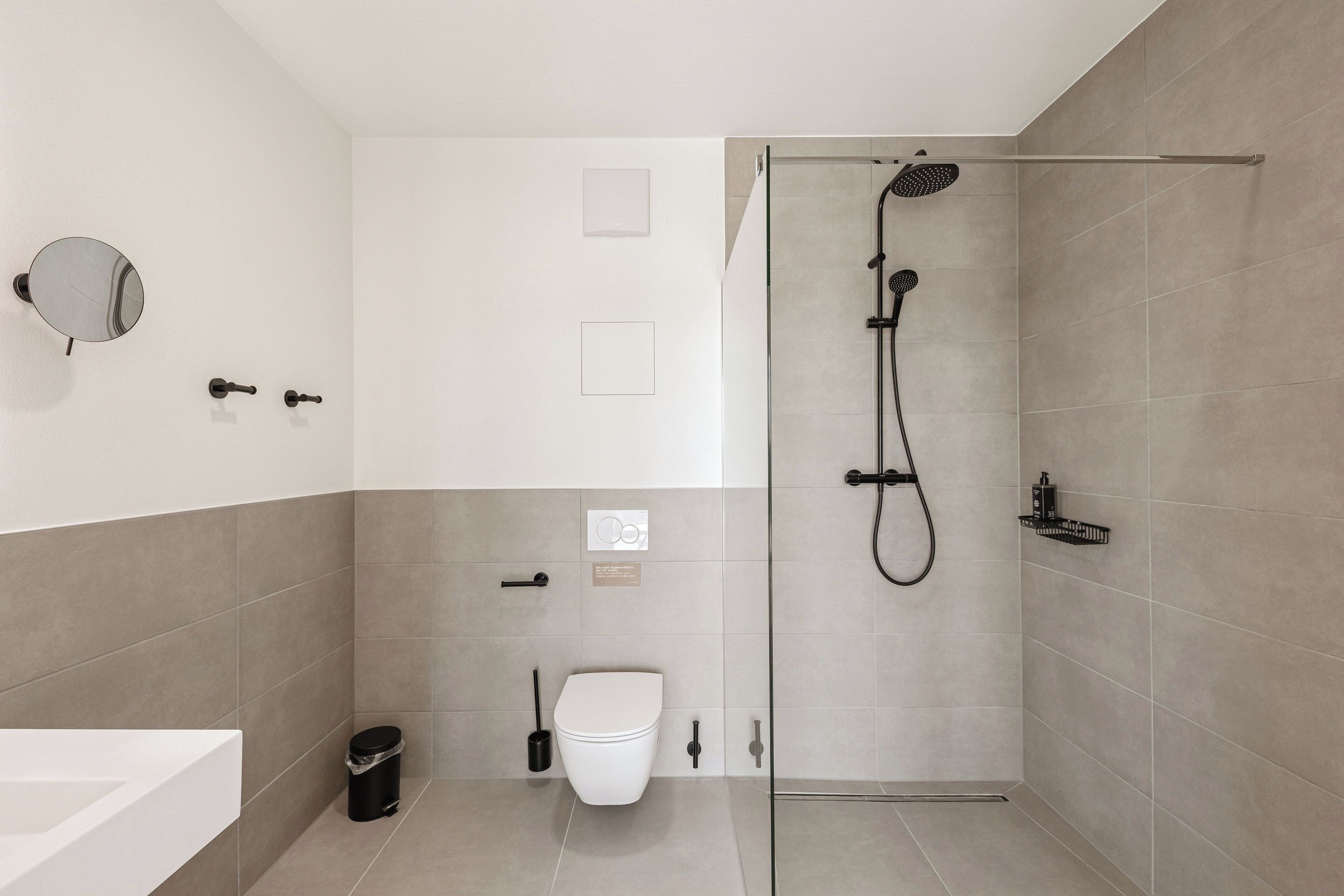 A modern bathroom with a shower, toilet, and sink.