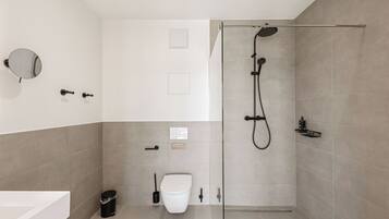A modern bathroom with a shower, toilet, and sink.