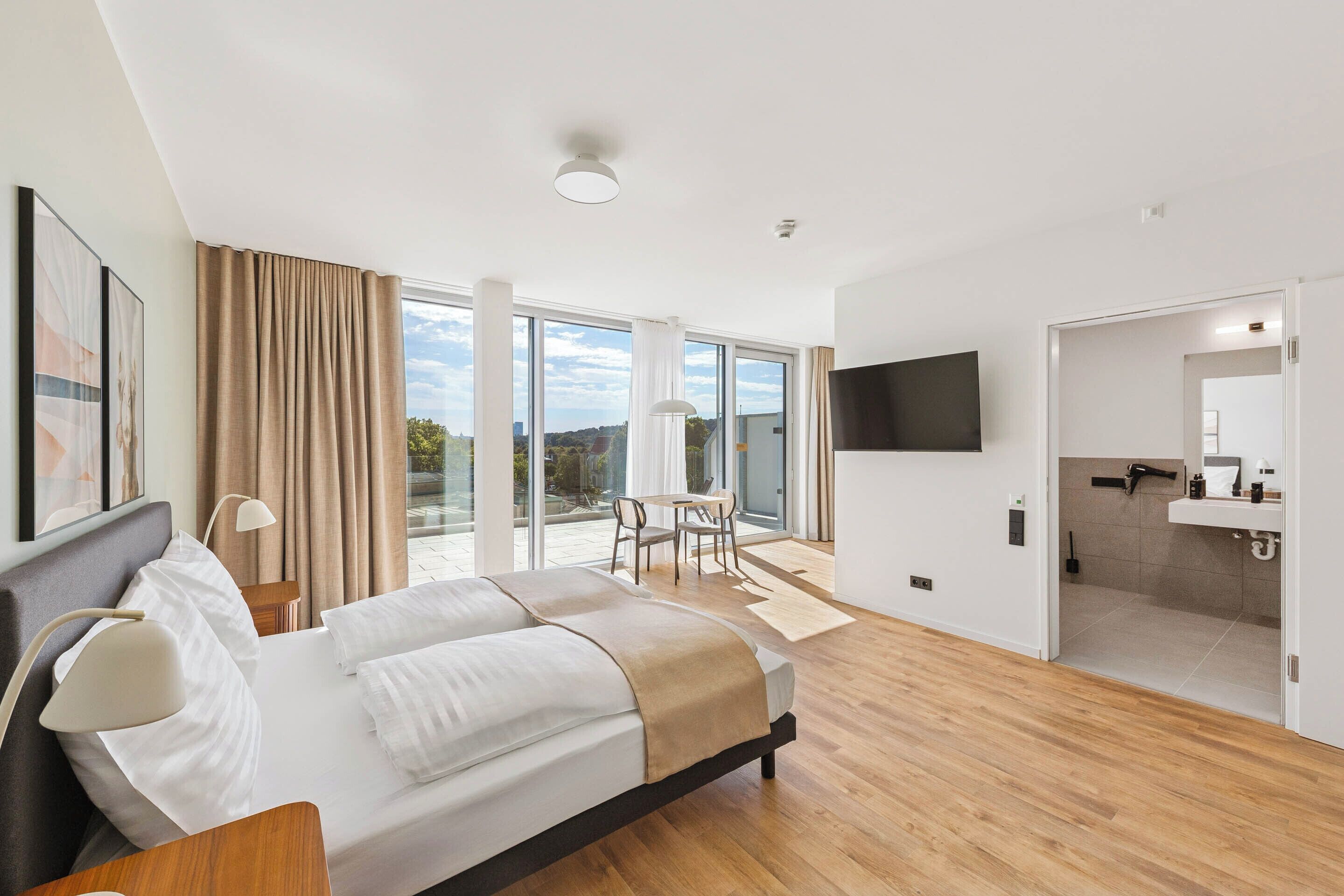 Ein modernes Hotelzimmer mit einem großen Bett, einem Schreibtisch und Blick ins Freie.